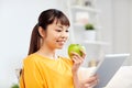 Happy asian woman with tablet pc and apple at home Royalty Free Stock Photo