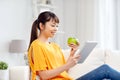 Happy asian woman with tablet pc and apple at home Royalty Free Stock Photo