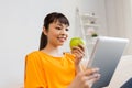 Happy asian woman with tablet pc and apple at home Royalty Free Stock Photo