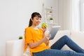 Happy asian woman with tablet pc and apple at home Royalty Free Stock Photo