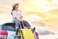 Happy Asian woman on top of car with luggage bag. Girl sitting on roof and looking sunset before night in evening. People Royalty Free Stock Photo