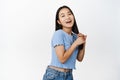 Happy asian woman touching her long dark healthy hair, advertising of haircare product, standing in blue tshirt over Royalty Free Stock Photo