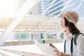 Happy Asian woman traveler tourist wanderer with trendy look searching direction on location map while traveling abroad in summer. Royalty Free Stock Photo