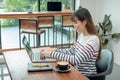 Happy asian woman using on laptop computer while working near wi Royalty Free Stock Photo