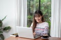 Happy asian woman using on laptop computer while working near wi Royalty Free Stock Photo