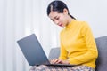 Happy asian woman using laptop while sitting on sofa in living room, WFH work from home concept Royalty Free Stock Photo