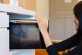 Happy asian woman using microwave oven in home kitchen