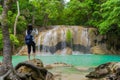 Happy Asian woman using mobile phone to take a photo by camera on social media at Erawan waterfall in tropical forest with trees Royalty Free Stock Photo