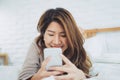 Happy Asian women are using smart phone on the bed in morning. Asian woman in bed checking social apps with smartphone. Royalty Free Stock Photo