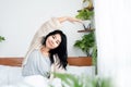 Happy Asian woman waking up and exercise in morning,  stretching arms in bed, and smiling Royalty Free Stock Photo