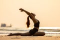 Happy Asian woman wearing black sport wear practice yoga Pigeon pose on the beach