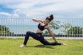 Happy Asian woman wearing black sport wear relaxing in yoga High Lunge twist pose with beautiful sea view