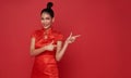 Happy Asian woman wearing traditional cheongsam qipao dress hand pointing to copy space isolated on red background. Happy Chinese