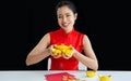 Happy Asian woman wearing traditional red costume, presenting and holding golds, smiling to celebrate Chinese New Year and make Royalty Free Stock Photo