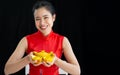 Happy Asian woman wearing traditional red costume, presenting and holding golds, smiling to celebrate Chinese New Year and make Royalty Free Stock Photo