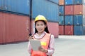 Happy Asian woman worker with helmet and safety vest using digital tablet and walkie talkie during inspection at logistic shipping Royalty Free Stock Photo