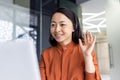 Happy Asian woman working inside office, businesswoman with video call headset talking and advising customers remotely Royalty Free Stock Photo