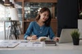 Happy asian woman writing making list taking notes in notepad working or learning on laptop indoors- educational course Royalty Free Stock Photo