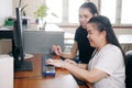 Happy Asian women co-workers in office workplace including person with blindness disability using computer with refreshable