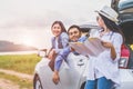 Happy Asian woman and her friends standing by car on coastal road at sunset. Young girl having fun during road trip. People Royalty Free Stock Photo