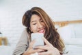 Happy Asian women are using smart phone on the bed in morning. Asian woman in bed checking social apps with smartphone. Royalty Free Stock Photo