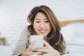 Happy Asian women are using smart phone on the bed in morning. Asian woman in bed checking social apps with smartphone. Royalty Free Stock Photo