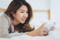 Happy Asian women are using smart phone on the bed in morning. Asian woman in bed checking social apps with smartphone. Royalty Free Stock Photo