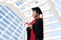 Happy Asian young beautiful graduate female student with University degree standing and holding diploma in hand after graduation Royalty Free Stock Photo