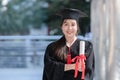 Happy Asian young beautiful graduate female student with University degree standing and holding diploma in hand after graduation Royalty Free Stock Photo