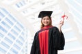 Happy Asian young beautiful graduate female student with University degree standing and holding diploma in raised hand Royalty Free Stock Photo