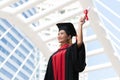 Happy Asian young beautiful graduate female student with University degree standing and holding diploma in raised hand Royalty Free Stock Photo