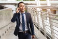 Happy asian young businessman using mobile phone. Man talking to clients via cell phone have a smile on his face in the city Royalty Free Stock Photo
