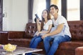Happy asian young couple on the couch watching a movie together. Royalty Free Stock Photo