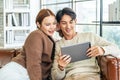 Happy couple enjoying their day together while using a tablet device on a luxurious leather couch