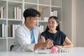 Happy asian young couple love hand put coin in piggy bank for save money. Business finance, deposit with banking for Royalty Free Stock Photo