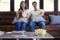 Happy asian young couple loving on the couch watching a movie to Royalty Free Stock Photo