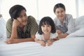 Happy Asian young family lying on bed under blanket at bedroom Royalty Free Stock Photo