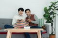 Happy Asian young gay couple wearing sweater holding joysticks playing game with excited face have fun together at home Royalty Free Stock Photo