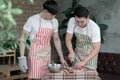 Happy Asian young LGBT gay couple with apron cooking together. Handsome man cutting tomato cucumber and his boyfriend at home Royalty Free Stock Photo