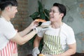 Happy Asian young LGBT gay couple making pizza together. Handsome man feeding sliced homemade pizza to his boyfriend taste