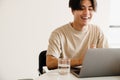 Happy asian young man smiling while using laptop computer at home Royalty Free Stock Photo