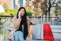 Happy asian young woman calling using a cell phone sitting on a bench. One chinese lady smiling and talking by Royalty Free Stock Photo