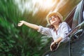 Happy Asian young woman enjoying a ride in a car with hand greeting Royalty Free Stock Photo