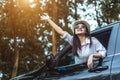 Happy Asian young woman enjoying a ride in a car with hand greeting. Royalty Free Stock Photo