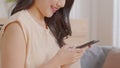 Happy asian young woman smile using smartphone surfing internet and enjoy with social media or online shopping at home. Modern Royalty Free Stock Photo