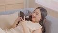 Happy asian young woman smile using smartphone surfing internet and enjoy with social media or online shopping at home. Modern Royalty Free Stock Photo