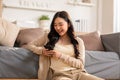 Happy asian young woman smile using smartphone surfing internet and enjoy with social media or online shopping at home. Modern Royalty Free Stock Photo