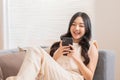 Happy asian young woman smile using smartphone surfing internet and enjoy with social media or online shopping at home. Modern Royalty Free Stock Photo