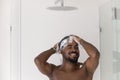 Happy athletic handsome African guy washing hair, taking shower