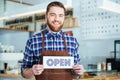Happy attactive young barista holding open sign at coffee shop Royalty Free Stock Photo